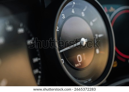 Close view of a speedometer and dashboard, showcasing precise details of the luxury car's instrumentation as sunlight reflects on the surface.