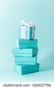 Close View The Stack Of Tiffany Boxes Tied With Silk Ribbon, Lying On Each Other On Tiffany Blue Color Pastel Background. Gift Festive Selection.