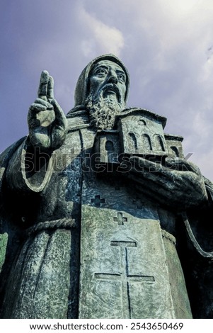 A close up view of the statue of Saint Methodius holding a church in Skopje Macedonia during daylight with a cloudy sky