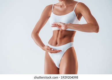 Close up view of stomach. Beautiful woman with slim body in underwear is in the studio.