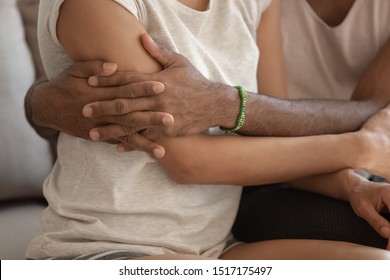 Close up view strong man hugs fragile lady, loving husband embracing cuddling beloved wife, african enamored couple experience sincere deep feelings showing each other love care and protection concept