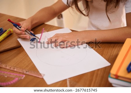 A close view of a student hands working with geometry tools on a paper at a desk. The composition includes a compass and triangular ruler, showcasing education and focus.