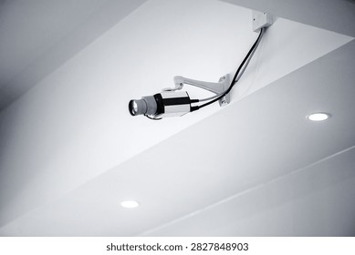 Close view of surveillance camera installed on white ceiling representing security monitoring technology safety and modern building infrastructure