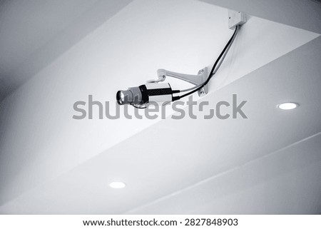 Close view of surveillance camera installed on white ceiling representing security monitoring technology safety and modern building infrastructure