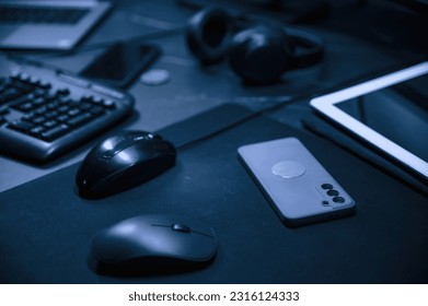 Close up view of table with smartphone, pc mouse, keyboard and headphones.