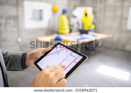 Close up view of tablet computer display showing project blueprint plan at construction site.