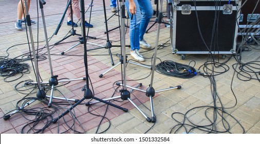 Close Up View Of Tangled Black Wires And Cables Plugged And Microphone Stand On The Ground, Chaos After Outdoor Concert