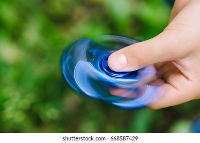 Close up view Teen boy playing a fidget spinner outdoors
