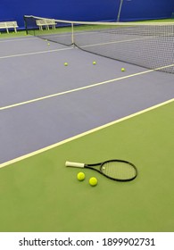 Close Up View Of Tennis Racket And Two Balls On The Green Clay Tennis Court.