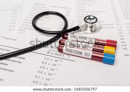 Close up view of test tubes with hormone and insulin tests of blood near stethoscope and lists with hormones
