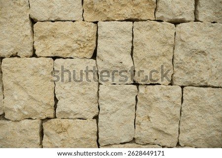 A close up view of a textured rectangular limestone block stone wall