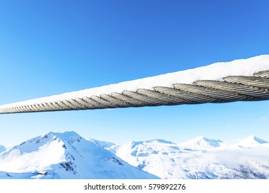 Close Up View Of Thick Steel Cable Cord Covered Stretched In Front Of Winter Mountain Landscape