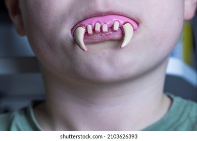 Close Up View Of Toy Vampire Teeth In Child's Mouth. Halloween, Prank Concept. Sweden. 