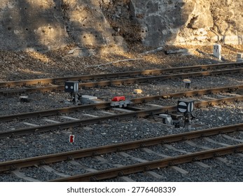 Close up view of a train track switch mechanism with black and white signal markers, highlighting railway signaling systems, transport technology, and safe train routing in a scenic outdoor setting