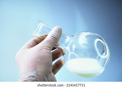Close up view of transparent glass test flask with white liquid inside. Isolated on grey backdrop. Laboratory tests and research.Chemistry science or medical biology experiment.Laboratory background. - Shutterstock ID 2141417711