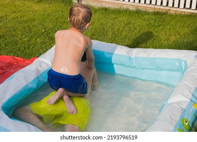 Close Up View Of Two Young Boys Fooling Around In Inflatable Pool On Backyard.