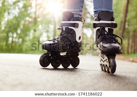 Close up view of unknown person rollerblading in park on sunny day, being on road, spending time in fresh air, enjoying hobby during vacation, fun free time activity. People and lifestyle concept.