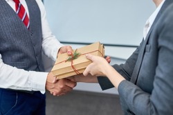 Close Up View Of Unrecognizable Businessman Shaking Hands With Female Colleague Presenting Her Gift For Boxing Day
