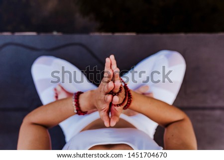 close up view of unrecognizable young asian woman doing yoga in a park. Sitting on the bridge with praying hands position and using Mala necklace. Yoga and healthy lifestyle concept. Top view