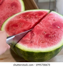A close up view of using the knife cut the fresh watermelon in the kitchen table in summer