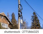 A close up view of a utility pole featuring tangled black cable loops and a grey junction box for high speed internet connectivity, representing modern digital infrastructure and rural development