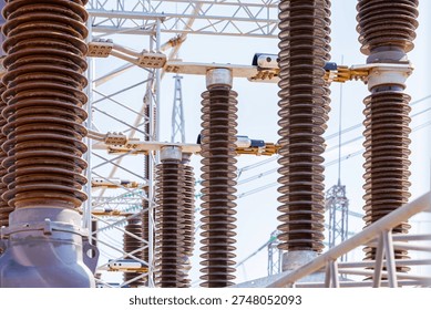 Close up view of various elements and high-voltage insulators of a transformer substation, without people, at daytime on background of blue sky