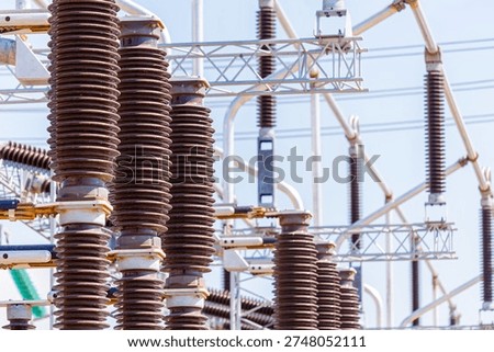 Close up view of various elements and high-voltage insulators of a transformer substation, without people, at daytime on background of blue sky