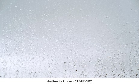 Close up view of water drops falling on glass. Rain running down on window. Rainy season, autumn. Raindrops trickle down, grey sky. - Powered by Shutterstock