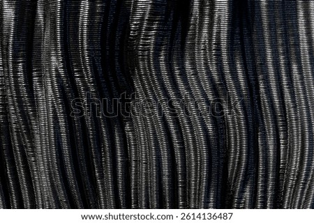 Close up view of wavy texture of shiny black carbon fiber, creating an elegant and futuristic background