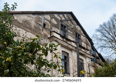 A close up view of a weathered facade with half timbered construction and broken windows in an abandoned manor house.