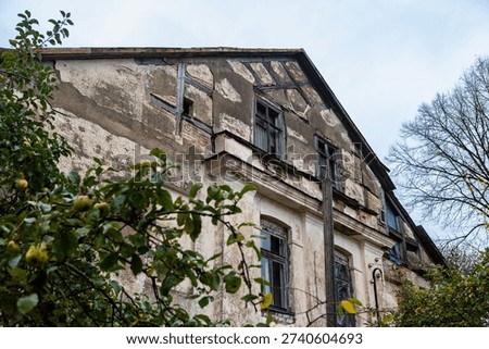 A close up view of a weathered facade with half timbered construction and broken windows in an abandoned manor house.