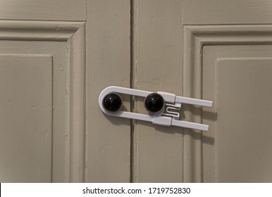 Close Up View Of A White Child Safety Lock Holding Two Cabinet Doors Together