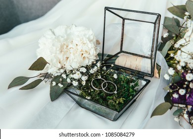 Close Up View Of White Flowers, Wedding Rings In Rustic Box With Plants Inside