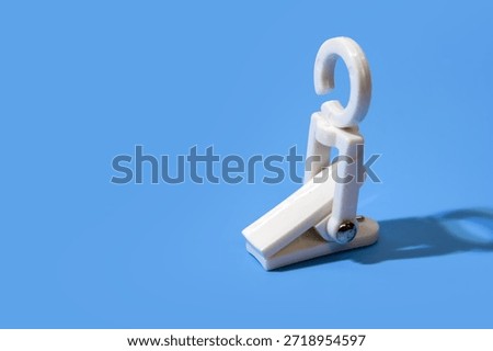 Close up view of white plastic clip unique with integrated hook on blue background with copy space.