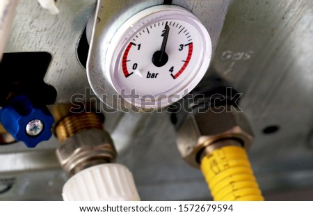 A close up view of white water pressure clock face of gas heater boiler, Pressure gauge of water and pipes under a boiler