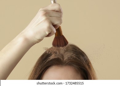 Close up view at woman applaying natural dry shampoo on hair roots. Brunette uses organic non-toxic chemicals free dry shampoo. Concept of healthy, low toxic, zero waste living.