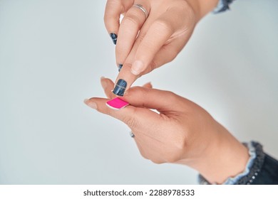 Close up view of a woman filing her nail after applying nail stickers. Manicure and beauty concept.