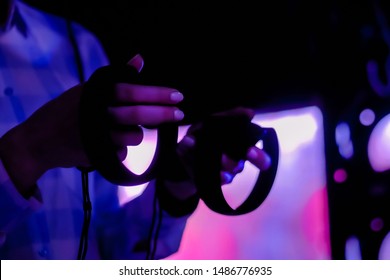 Close Up View Of Woman Hand Using Virtual Reality Controller Stick At Futuristic Low Light Exhibition. Gaming, Immersive, Technology, Video Game, VR And Leisure Time Concept