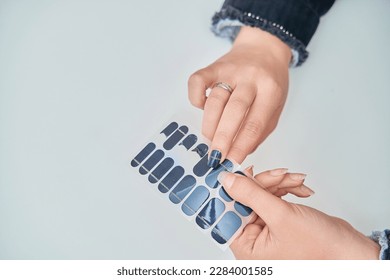 Close up view of a woman holding nail sticker decals. Manicure and beauty concept.
