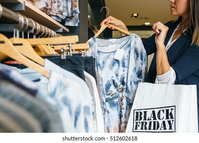 Close Up View Of A Woman Picking Up Blouse In Clothing Store. Holding Black Friday Marked Bag