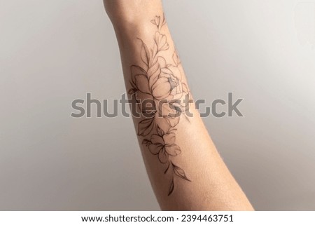 a close up view of woman showing her finished flowers tattoo on her hand