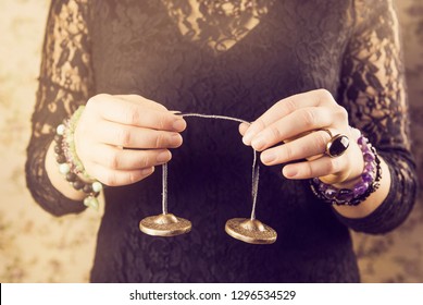 Close up view of woman using traditional Tibetan Tingsha bells (or Ting-Sha). Alternative sound therapy concept. Used in prayer and rituals. Bright positive back warm yellow light.