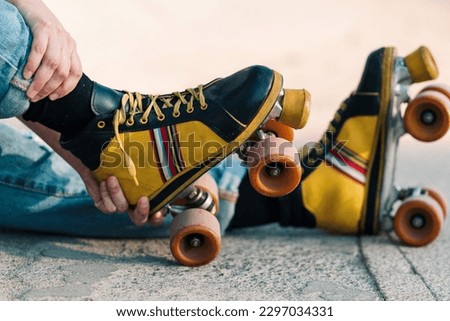 close up view of woman's hand arranging four-wheeled colored skates in a park with sunny day.