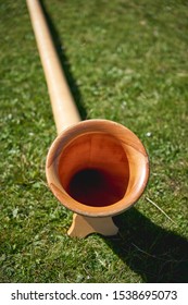 Close up view of a wooden Alpine horn (also Alphorn or Alpenhorn), a straight several-meter-long wooden natural horn of conical bore, with a wooden cup-shaped mouthpiece. Portrait format.
