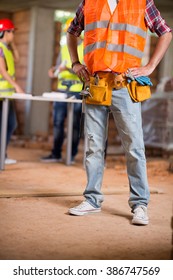 Close up view of workers belt with tools and protective vest
