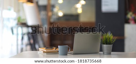 Close up view of worktable with laptop, supplies, stationery and plant pot in office room 