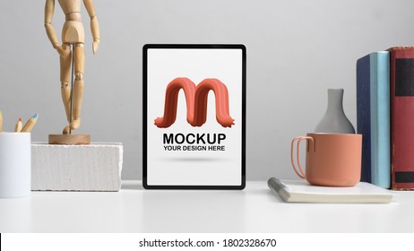 Close up view of worktable with mock up tablet, stationery, books, mug and decorations in home office 