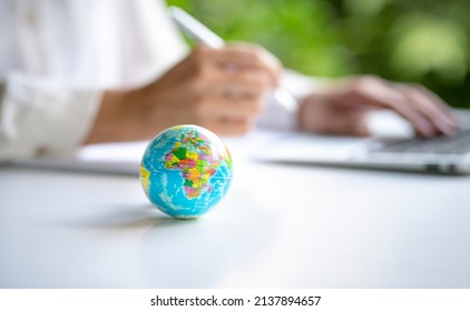 Close up view of world globe with businesswoman and computer laptop at the background. Copy space. - Shutterstock ID 2137894657