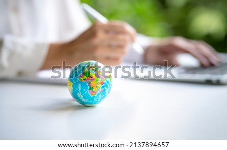 Close up view of world globe with businesswoman and computer laptop at the background. Copy space.