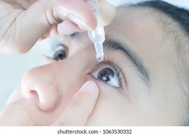 Close up view of young asian woman applying eye drop to left eye, artificial tears. - Shutterstock ID 1063530332